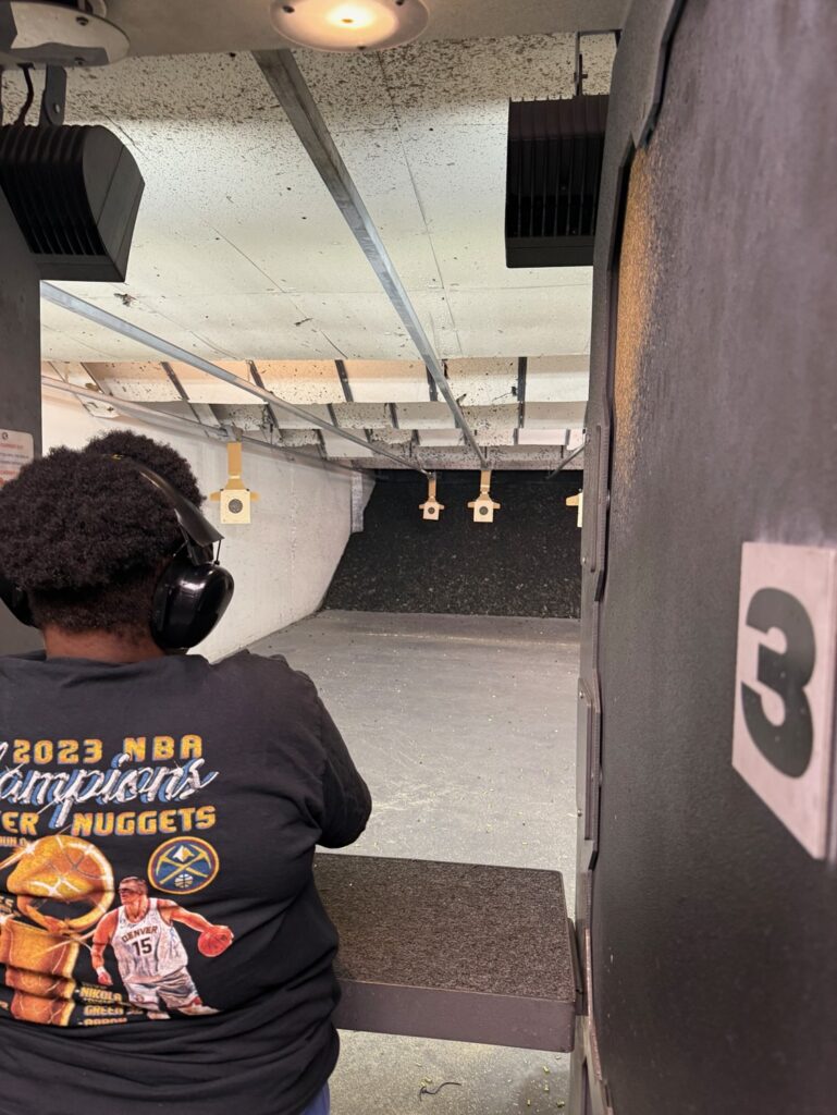 Student practicing pistol shooting in an indoor range lane