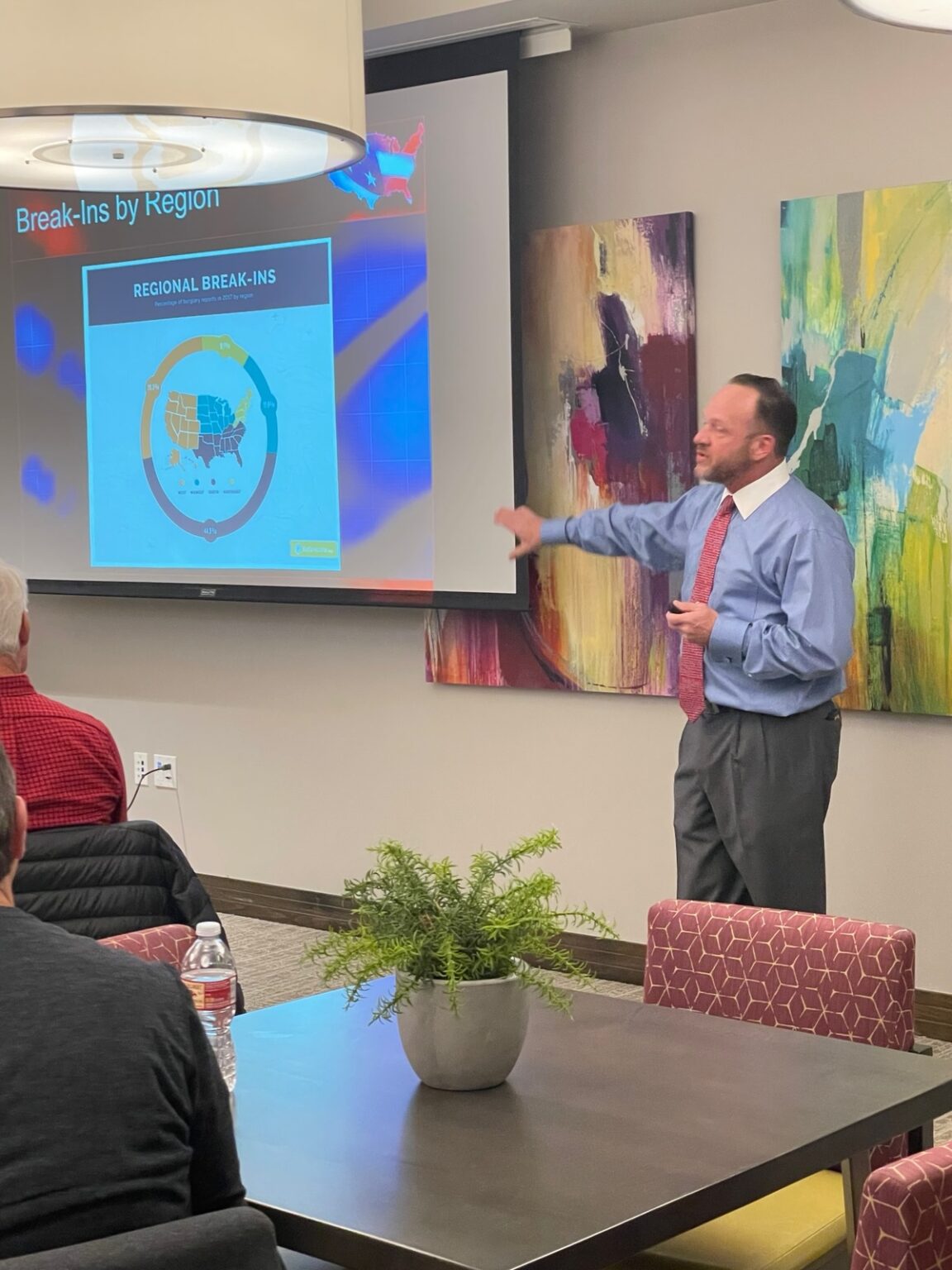 John Rader teaching a self-defense seminar, pointing to a chart of break-ins by region