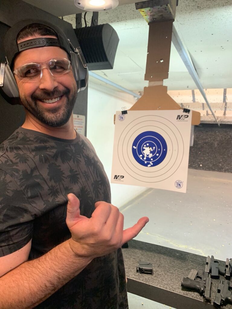 Student holding a pistol target showing a tight shot group after training